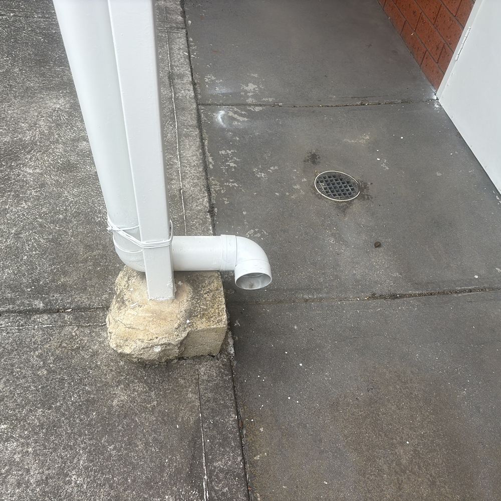 Downpipe emptying onto the ground instead of into stormwater, found during a pre-purchase inspection in Braybrook